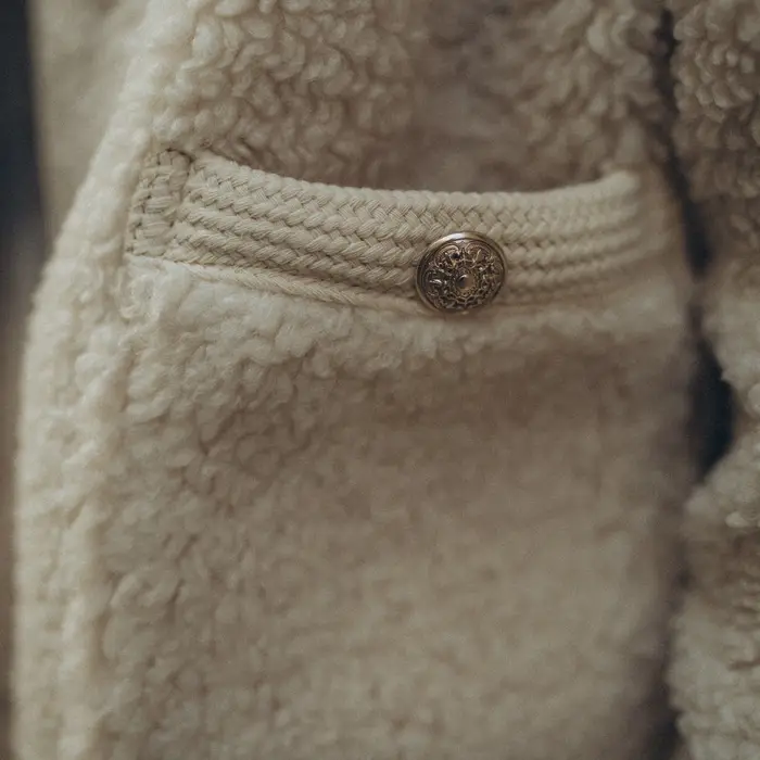 Close-up of an oat-colored high-pile fleece with a buttoned chest pocket