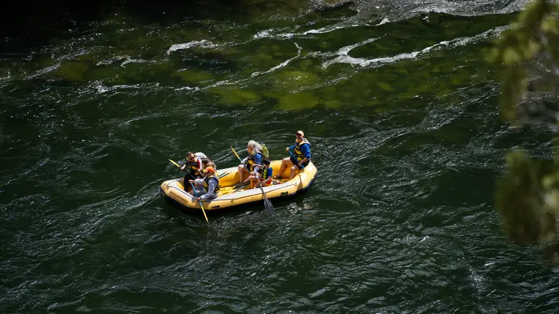 Raft crew paddling a yellow raft down a dark green river